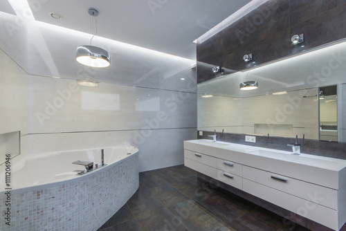 Gorgeous bathroom design with light tiles on the walls and dark on the floor. A bathtub and a huge mirror over a cabinet with a sink.