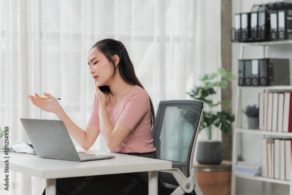 Focused on the Task: A young woman in a pink shirt sits at her desk, her attention focused on her laptop and pen, highlighting a moment of professional concentration and dedication. Focused on the Task: A young woman in a pink shirt sits at her desk, her attention focused on her laptop and pen, highlighting a moment of professional concentration and dedication.