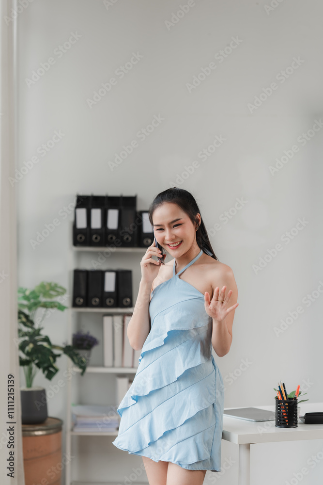 Businesswoman Celebrates Success: A radiant young woman in a stylish blue dress exudes confidence and joy as she takes a break from her work, celebrating a successful call. Businesswoman Celebrates Success: A radiant young woman in a stylish blue dress exudes confidence and joy as she takes a break from her work, celebrating a successful call.
