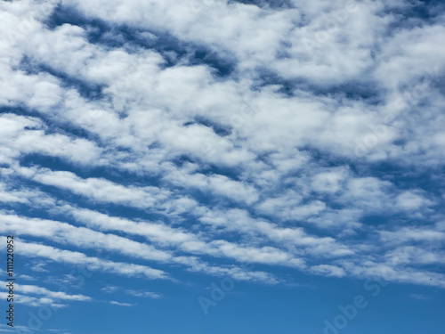 Fluffy white clouds lie in stripes against the blue sky