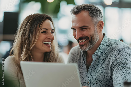 Happy couple working on a laptop in a cozy café environment, sharing joyful moments together