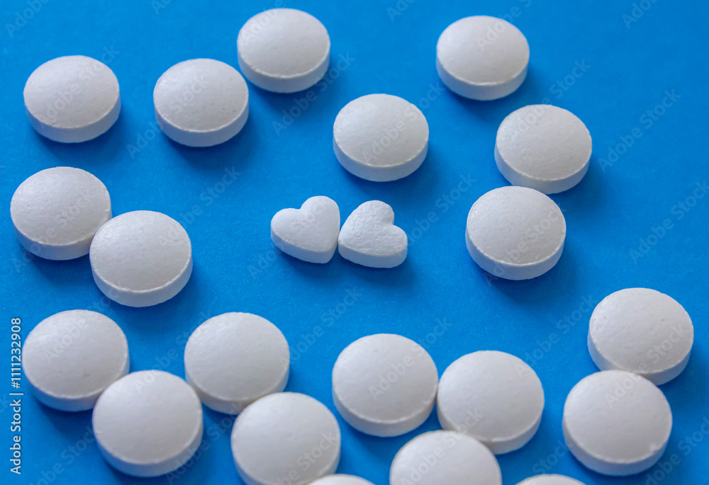 Heart shaped and round white pills on blue background. Global healthcare concept. Health and Medicine. Love concept for Valentine's day with love pills. Heart shaped and round white pills on blue background. Global healthcare concept. Health and Medicine. Love concept for Valentine's day with love pills.