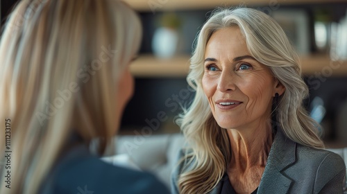 Smiling middle aged female manager engaging with assistant in a modern office team meeting