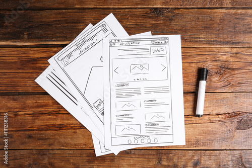 Developing UI design. Sketches of website wireframes and felt pen on wooden table, top view photo