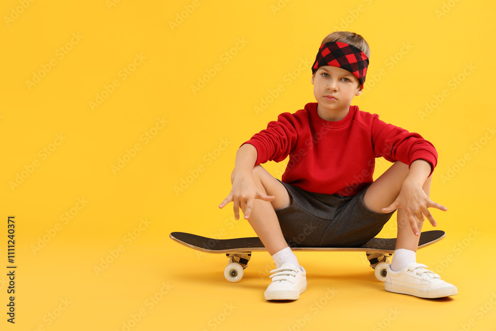Little boy with skateboard on yellow background, space for text Little boy with skateboard on yellow background, space for text