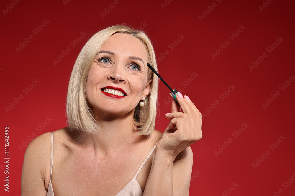 Fototapeta premium Smiling woman with makeup brush on red background. Space for text