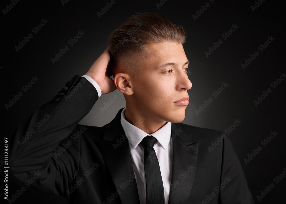 Confident young man with stylish haircut on black background