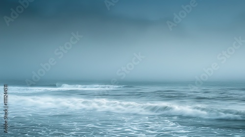 Serene view of the ocean with gentle waves under a misty, overcast sky, creating a peaceful and tranquil seascape atmosphere.