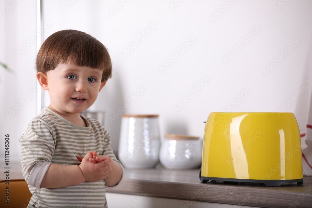 Little boy playing with toaster in kitchen. Dangerous situation Little boy playing with toaster in kitchen. Dangerous situation