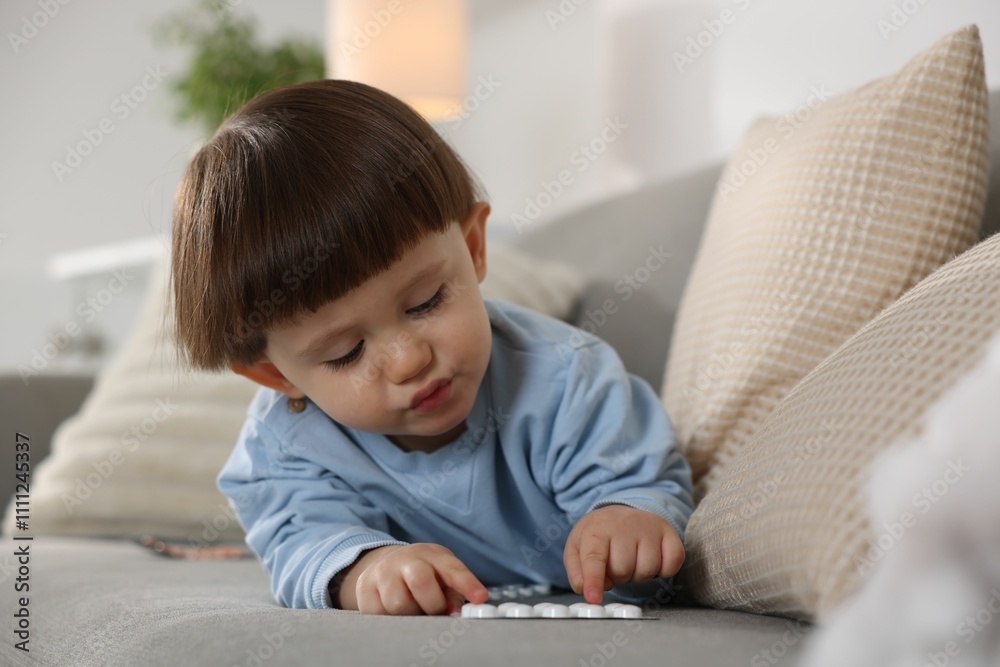 Little boy playing with pills on sofa at home. Child in danger Little boy playing with pills on sofa at home. Child in danger