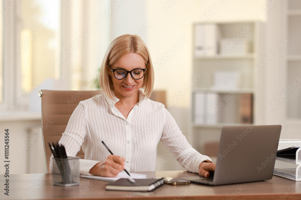 Smiling middle aged woman working at table in office Smiling middle aged woman working at table in office
