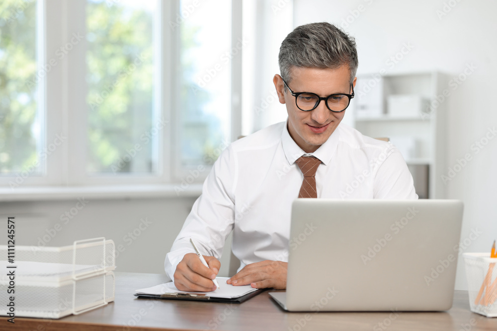 Middle aged man working at table in office Middle aged man working at table in office