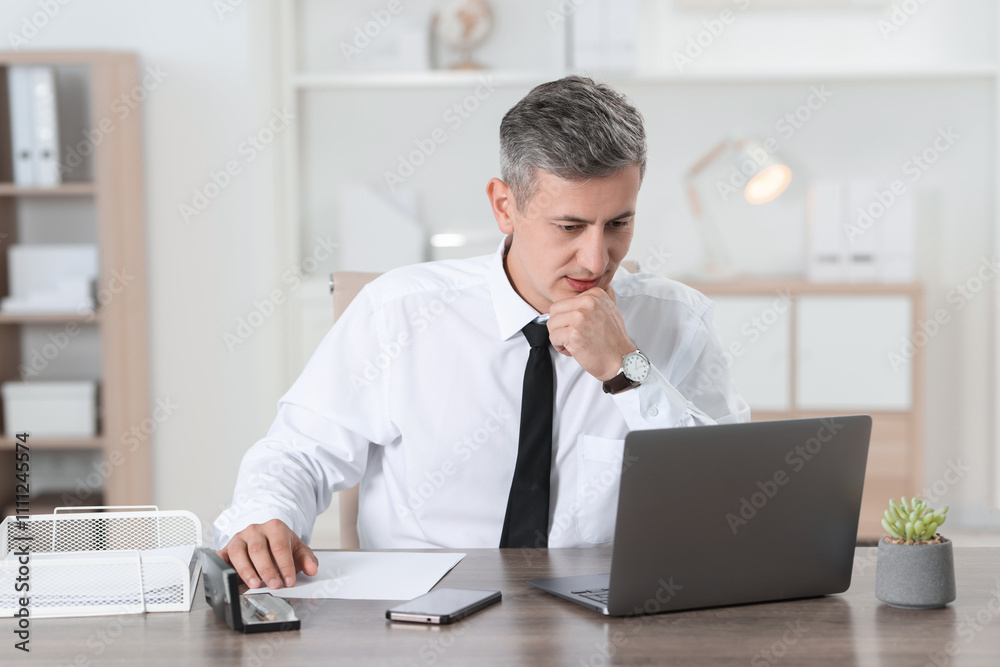 Businessman working with laptop at table in office Businessman working with laptop at table in office