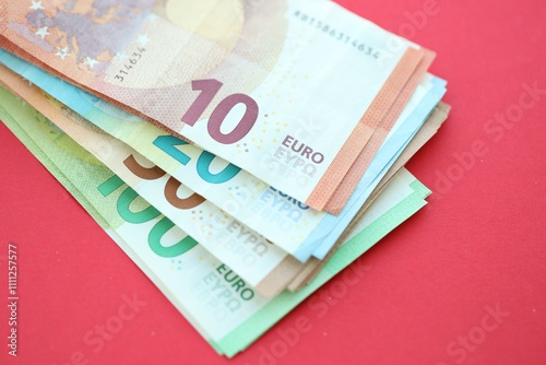 Big amount of one hundred, twenty, ten and fifty euro money bills on red background photo