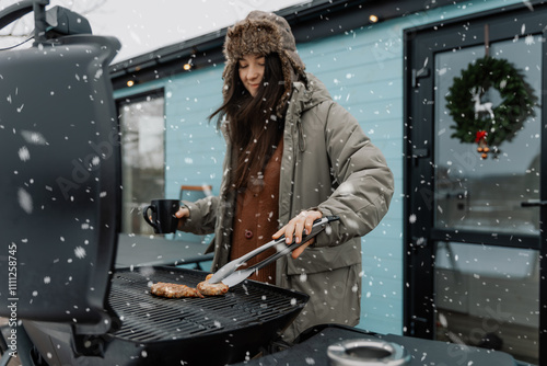 A young woman is grilling a barbecue outside her house in winter. natute. Lifestyle. the concept of a winter holiday in nature