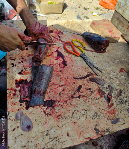 Cutting fish on the table. Fish market. A man cleans the entrails and cuts a catfish into pieces. Day. Autumn. Egypt.