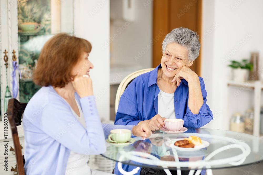 Two senior women share a joyful conversation over tea in a charming cafe. They enjoy pastries while relaxing in a warm and inviting atmosphere, showcasing their vibrant lifestyle. Two senior women share a joyful conversation over tea in a charming cafe. They enjoy pastries while relaxing in a warm and inviting atmosphere, showcasing their vibrant lifestyle.