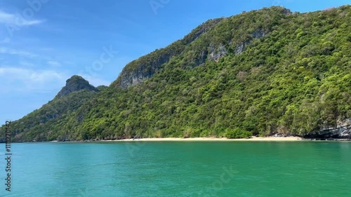 Lush green hillside along a serene turquoise beach in Ang Thong National Park, Thailand