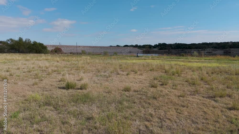 Drone captures panning shot above lake edge lush greenery and open landscape Drone captures panning shot above lake edge lush greenery and open landscape