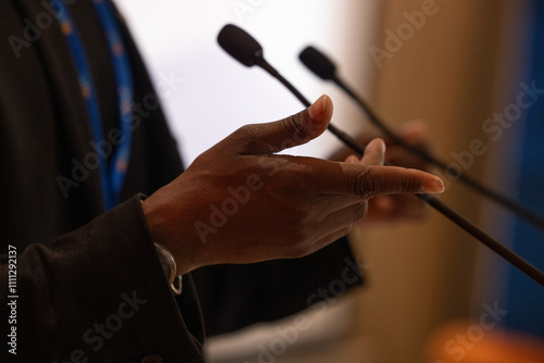 focus sur un micro et les mains d'un orateur prononçant un discours à la tribune lors d'un meeting politique, d'un colloque ou d'une réunion	