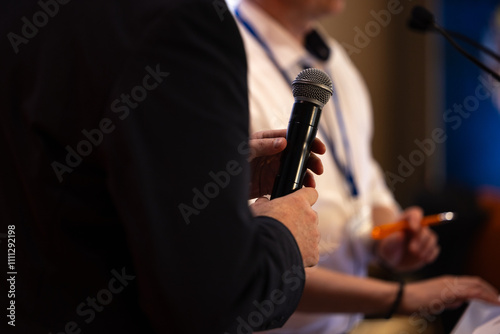 focus sur un micro et les mains d'un orateur prononçant un discours à la tribune lors d'un meeting politique, d'un colloque ou d'une réunion	