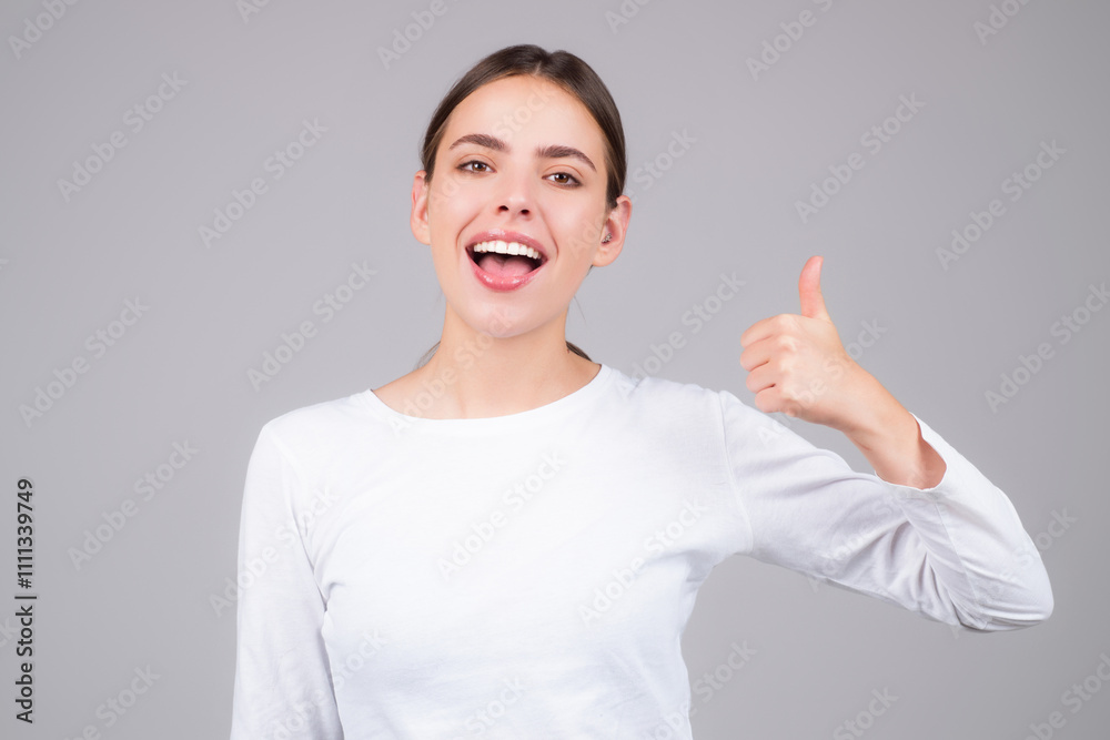 Young Girl show thumb up isolated on gray background. Female hand showing thumb up. A hand giving a thumbs up. Happy Woman with thumb up.