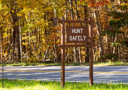 An engraved, wooden sign stating Hunt Safely, on the side of the road in the woods in Venango County, Pennsylvania, USA on a sunny fall day photo