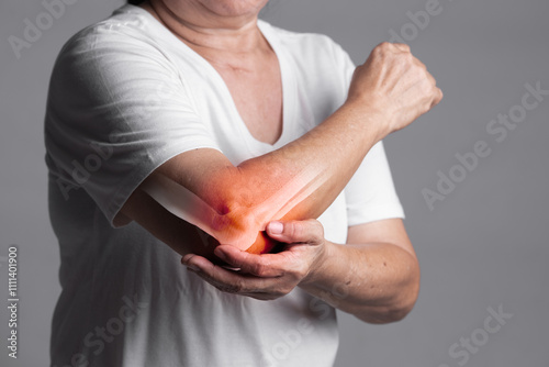 X-ray of elbow,Woman in her 70s holding her elbow with a red pain point. elbow paint and joint pain concept