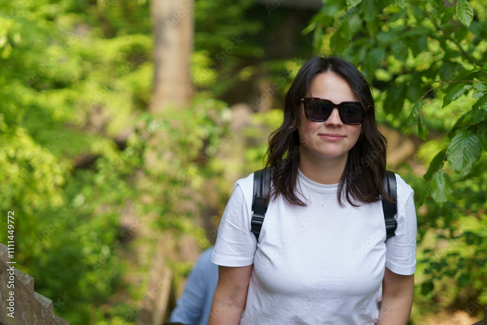 Beautiful smiling dark-haired girl in a white T-shirt and with a backpack on her shoulders in the summer on a trip. Pedestrian wanderung concept Beautiful smiling dark-haired girl in a white T-shirt and with a backpack on her shoulders in the summer on a trip. Pedestrian wanderung concept