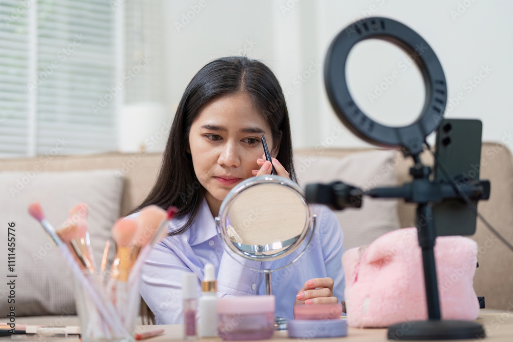 Asian woman perfecting eyebrow makeup in home studio Asian woman perfecting eyebrow makeup in home studio