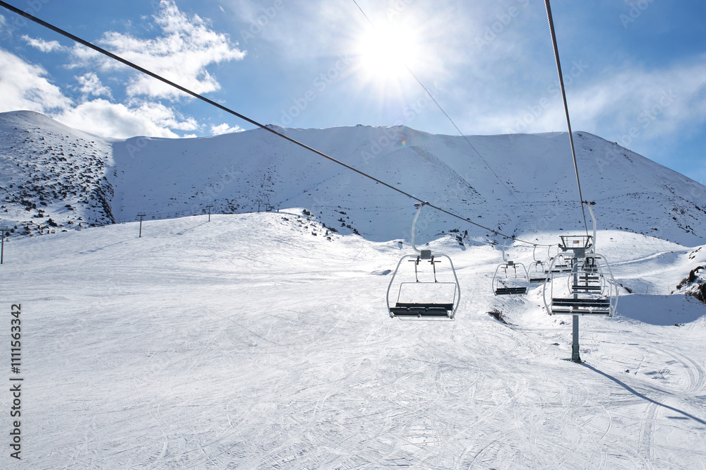 Cableway chairlift, lift without people at ski resort, winter activity, sunny day. Nobody at mountain slope. First visitor at Chunkurchak ski lodge, Kyrgyzstan. Cableway chairlift, lift without people at ski resort, winter activity, sunny day. Nobody at mountain slope. First visitor at Chunkurchak ski lodge, Kyrgyzstan.
