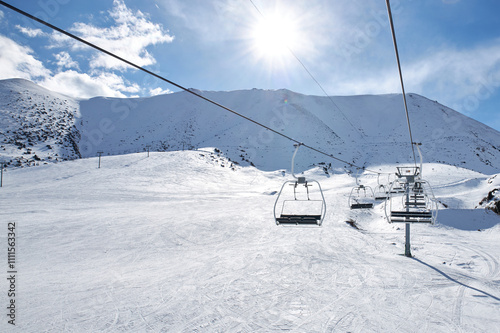 Cableway chairlift, lift without people at ski resort, winter activity, sunny day. Nobody at mountain slope. First visitor at Chunkurchak ski lodge, Kyrgyzstan. photo