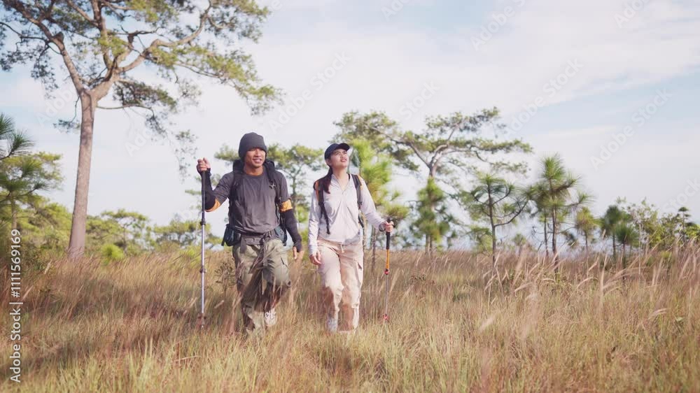 A man and woman are walking through a grassy field. The man is wearing a backpack and the woman is wearing a hat. Scene is peaceful and serene, as the couple enjoys their time together in nature A man and woman are walking through a grassy field. The man is wearing a backpack and the woman is wearing a hat. Scene is peaceful and serene, as the couple enjoys their time together in nature