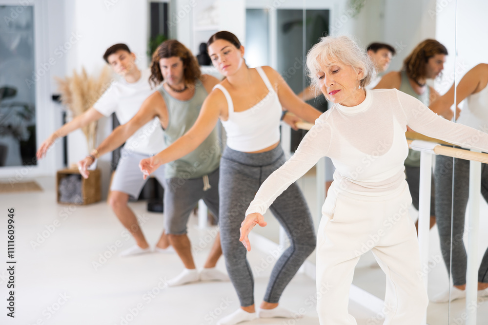 Fototapeta premium Women and men training in ballet class with other dancers