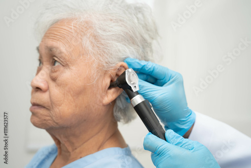 Otolaryngologist or ENT physician doctor examining senior patient ear with otoscope, hearing loss problem.