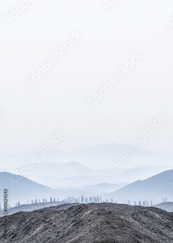 Misty mountain landscape with layers of rolling hills and distant trees during early morning