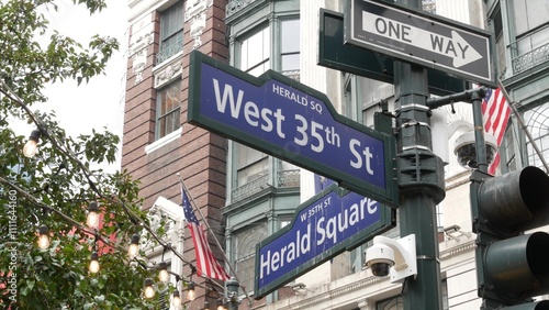 New York City crossroad, Manhattan Broadway street intersection road sign. NYC Midtown district architecture, Herald Square park, 6 Sixth avenue, United States. American flag. One way arrow road sign.