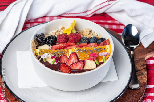 An Acai bowl topped with granola, banana, watermelon, oranges, berries