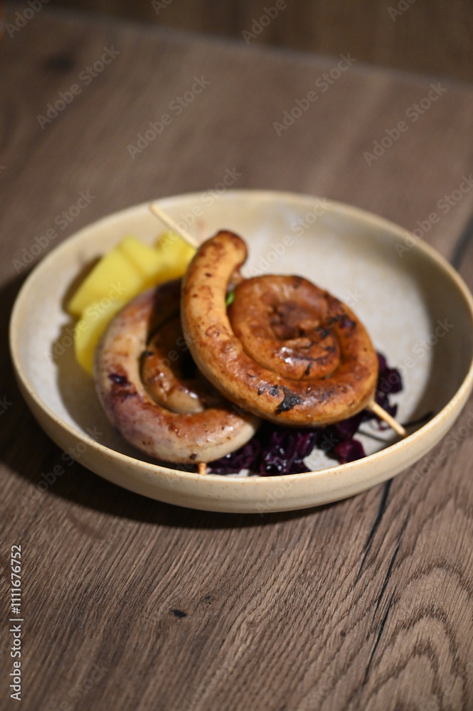 A beautifully plated dish featuring a grilled spiral sausage on a skewer, served with creamy mashed potatoes and braised red cabbage. A beautifully plated dish featuring a grilled spiral sausage on a skewer, served with creamy mashed potatoes and braised red cabbage.