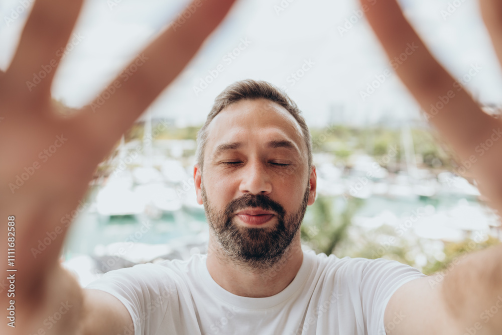 Smiling man with beard and closed eyes takes selfie on a yachts view Smiling man with beard and closed eyes takes selfie on a yachts view