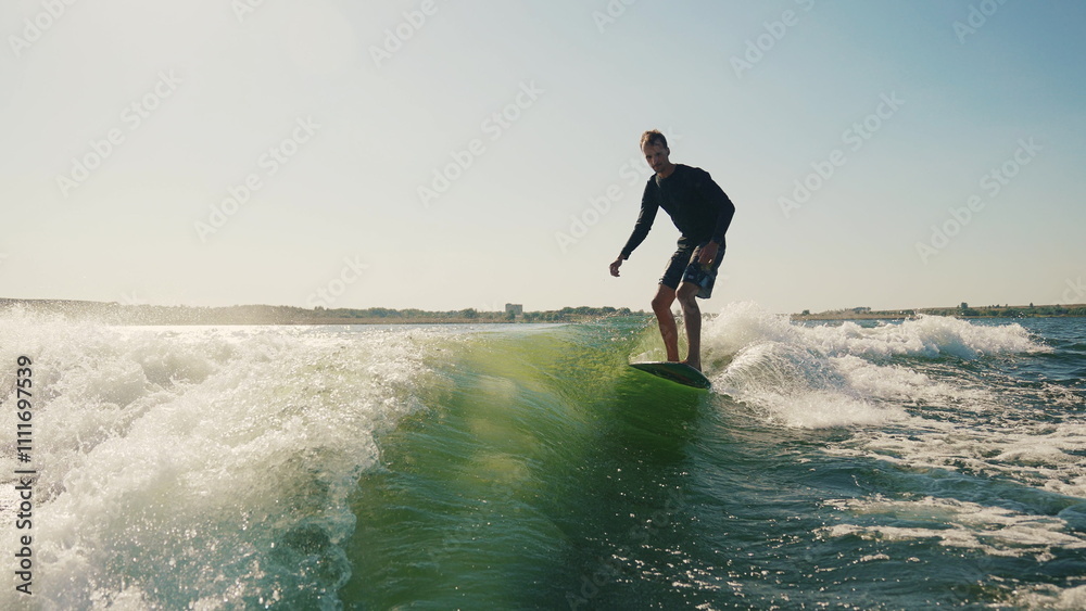 Wakeboarding behind a motorboat on the surface of the water. The scene conveys the dynamics, speed and adrenaline of water extreme sports. A man performs tricks while balancing on a wakeboard. Wakeboarding behind a motorboat on the surface of the water. The scene conveys the dynamics, speed and adrenaline of water extreme sports. A man performs tricks while balancing on a wakeboard.
