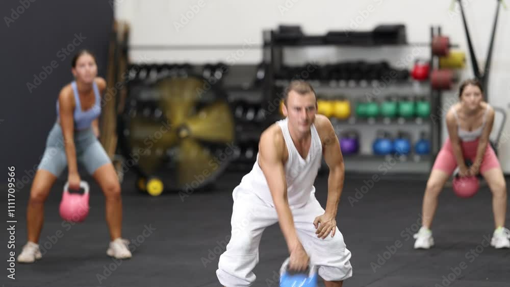 Young athletic man in sportswear training with kettlebell in gym Young athletic man in sportswear training with kettlebell in gym