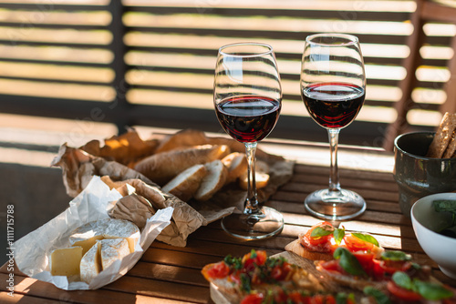 Red wine glasses with antipasto on the terrace table. Holiday dinner outdoors at sunset.
