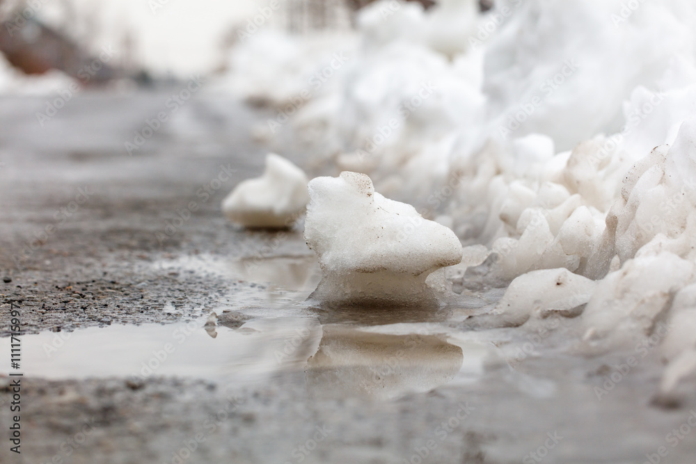 Φωτογραφία A snow covered road with a puddle of water and a large pile of snow