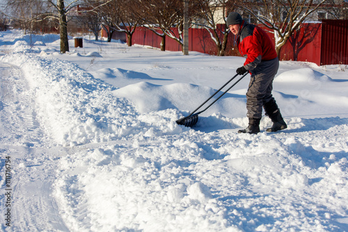 A man is shoveling snow from the sidewalk