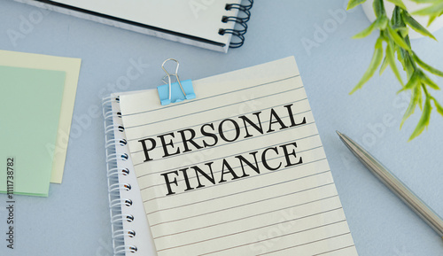 Text PERSONAL FINANCE on Office desk table with keyboard, notepad and analysis chart on a blue background photo