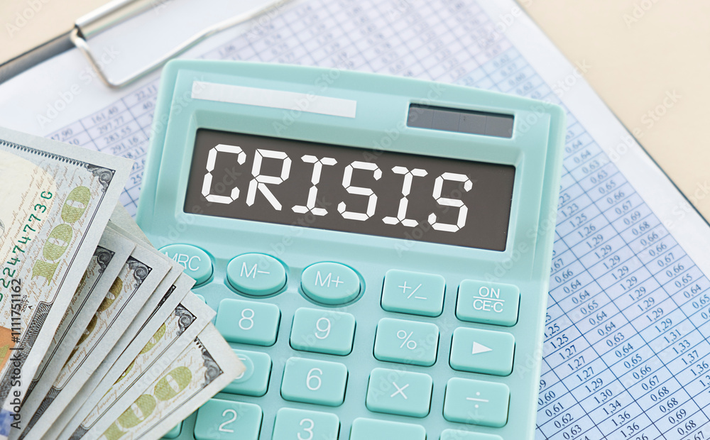 A calculator with the inscription CRISIS is placed in the stack of documents. A calculator with the inscription CRISIS is placed in the stack of documents.