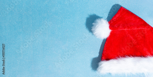 Christmas red Santa Claus hat on shiny blue background. Copy space