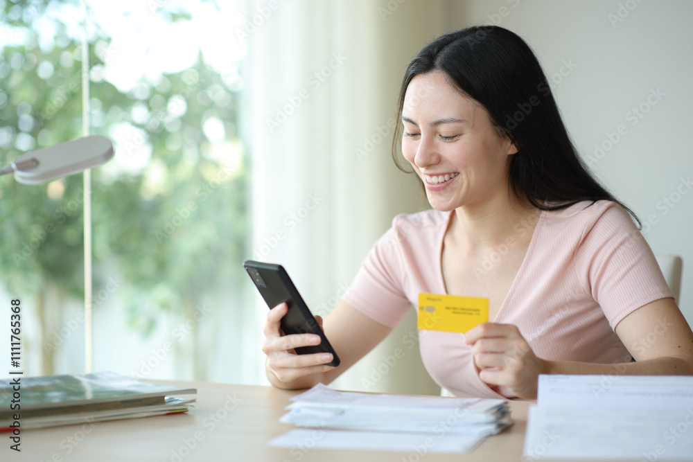 Happy asian woman paying invoices online with card Happy asian woman paying invoices online with card