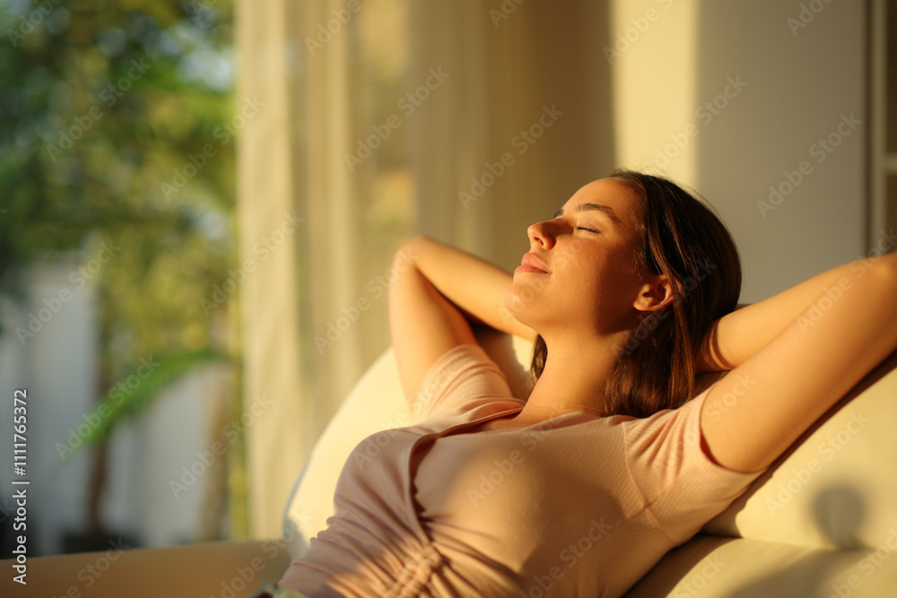 Woman relaxing at home at sunset on a sofa Woman relaxing at home at sunset on a sofa